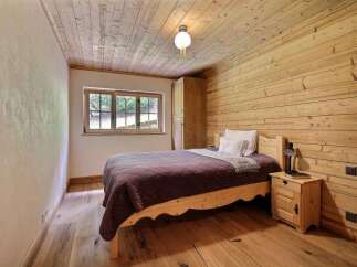 This cozy bedroom features a rustic design with wooden walls and flooring, creating a warm and inviting atmosphere.