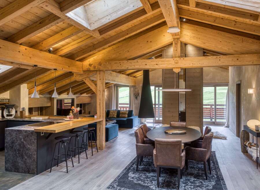 Experience luxury living in this stunning chalet, featuring a warm and inviting interior with exposed wooden beams and a cozy fireplace.