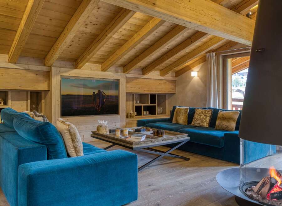 Experience luxury living in this stunning chalet, featuring a cozy living room with a fireplace and a plush blue sofa.