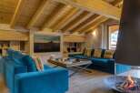 Experience luxury living in this stunning chalet, featuring a cozy living room with a fireplace and a plush blue sofa.