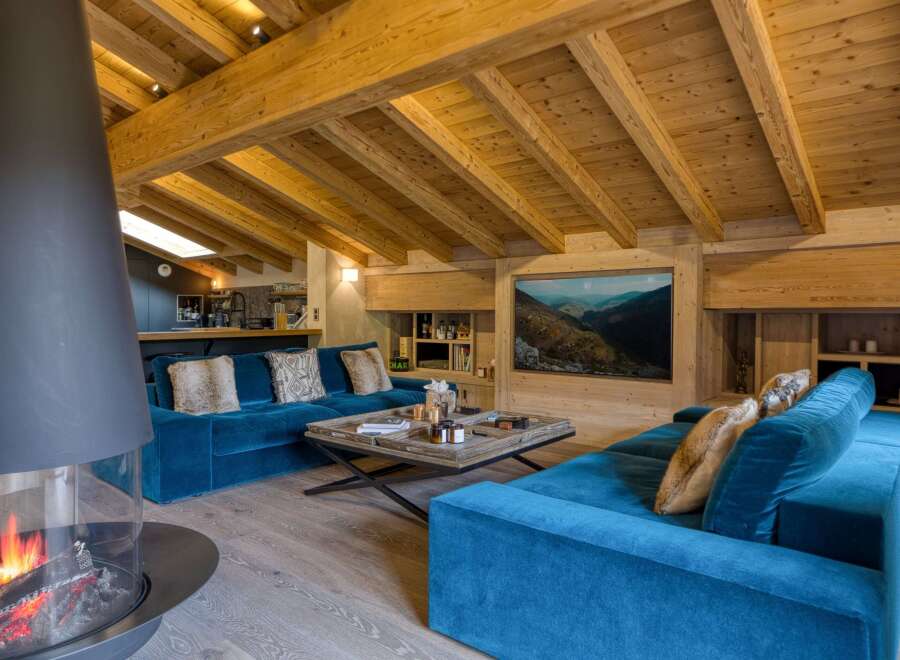 This luxurious living space features a stunning modern fireplace and a cozy blue velvet sofa, perfect for relaxing.