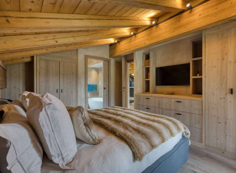 This luxurious bedroom showcases a stunning wooden ceiling and walls, creating a warm and inviting atmosphere.