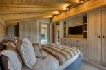 This luxurious bedroom showcases a stunning wooden ceiling and walls, creating a warm and inviting atmosphere.