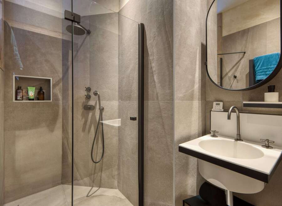 This modern bathroom features a sleek, minimalist design with a walk-in shower and a stylish sink.
