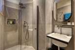 This modern bathroom features a sleek, minimalist design with a walk-in shower and a stylish sink.