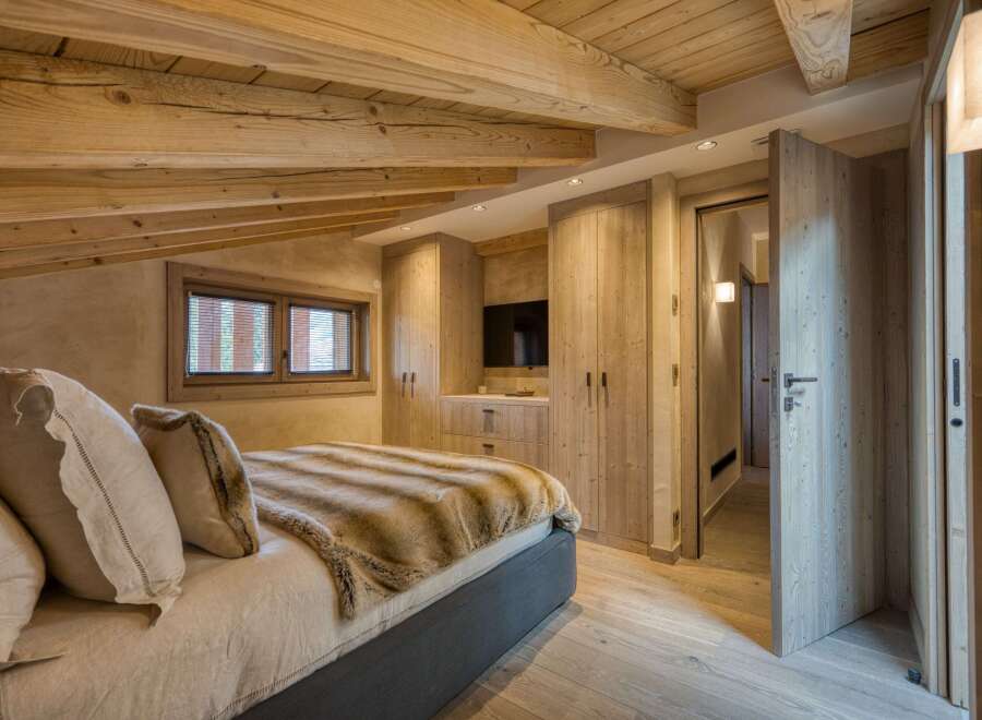 This luxurious bedroom boasts a rustic charm with its exposed wooden beams and warm, inviting tones.