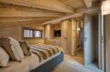 This luxurious bedroom boasts a rustic charm with its exposed wooden beams and warm, inviting tones.