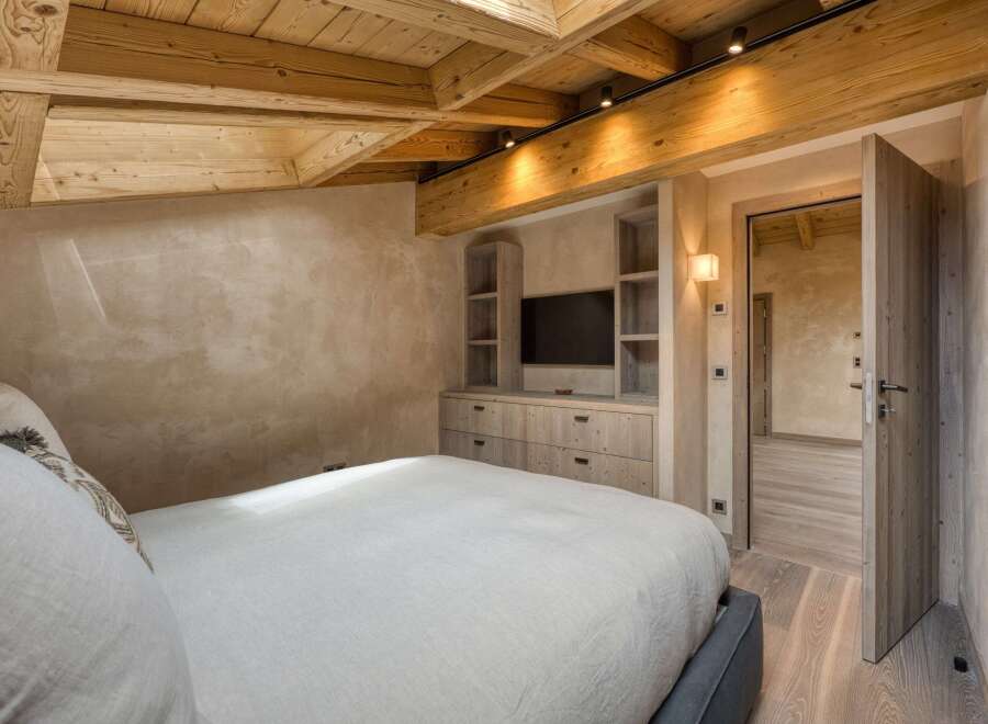 This luxurious bedroom boasts a stunning wooden ceiling and walls, creating a warm and inviting atmosphere.