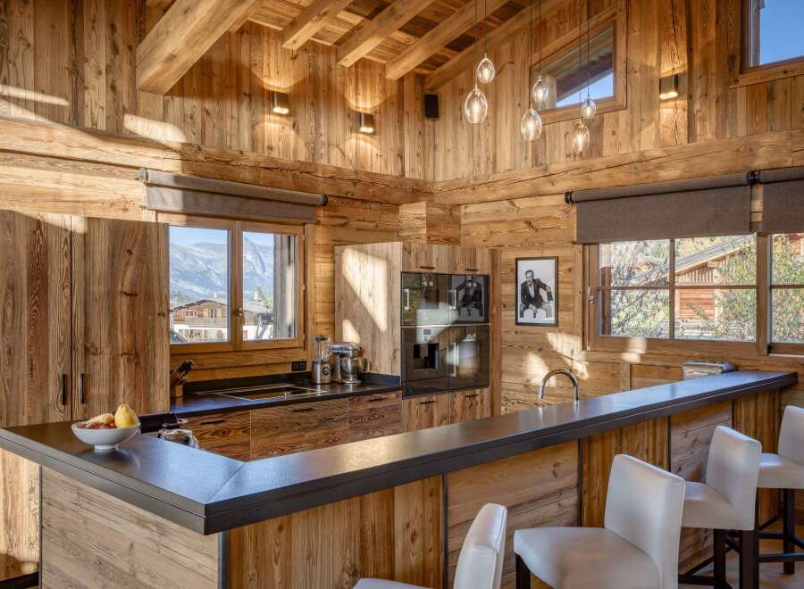 Experience the warmth of this stunning chalet kitchen, featuring exquisite wooden paneling and a sleek, modern design.
