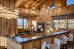 Experience the warmth of this stunning chalet kitchen, featuring exquisite wooden paneling and a sleek, modern design.