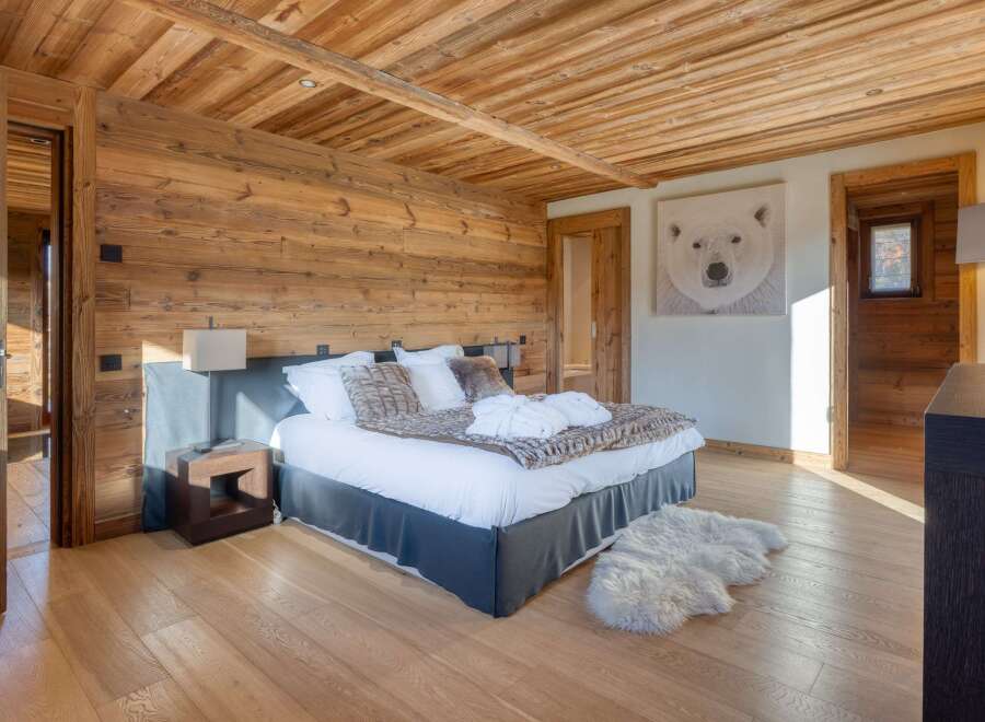 This luxurious bedroom boasts a rustic charm with its wooden walls and ceiling, creating a warm and inviting atmosphere.