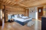 This luxurious bedroom boasts a rustic charm with its wooden walls and ceiling, creating a warm and inviting atmosphere.