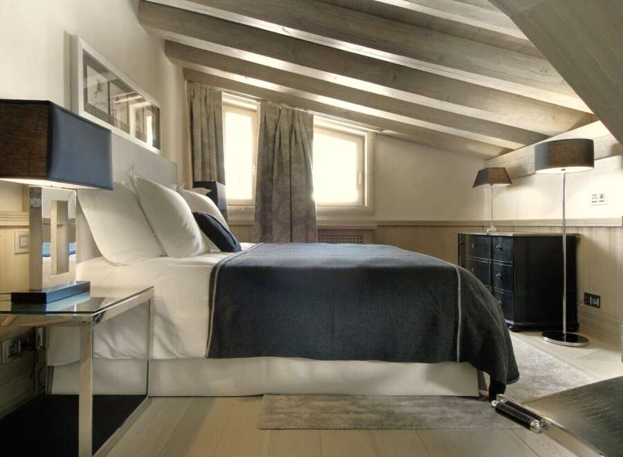 Experience luxury in this stunning bedroom featuring a cozy bed with plush pillows and a stylish throw.