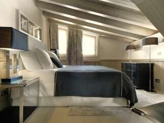 Experience luxury in this stunning bedroom featuring a cozy bed with plush pillows and a stylish throw.