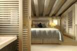 This cozy bedroom features a rustic design with exposed wooden beams and a light-filled ambiance.