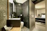 Step into luxury with this stunning bathroom, featuring sleek dark stone tiles and a modern design.