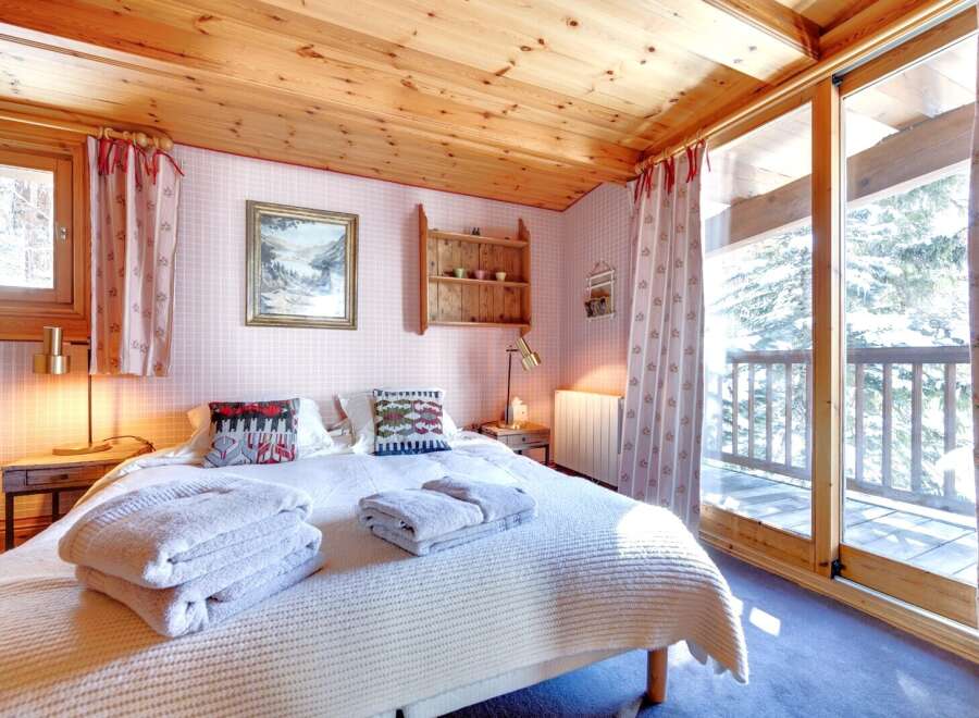 This cozy bedroom features a wooden ceiling and a comfortable bed with soft towels.