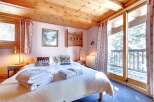 This cozy bedroom features a wooden ceiling and a comfortable bed with soft towels.