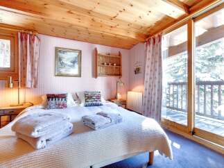 This cozy bedroom features a wooden ceiling and a comfortable bed with soft towels.