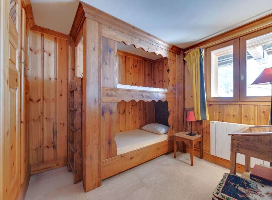 This charming bedroom features custom-built bunk beds crafted from warm, inviting wood, perfect for a cozy retreat.