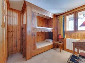 This charming bedroom features custom-built bunk beds crafted from warm, inviting wood, perfect for a cozy retreat.