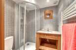 This charming bathroom features a modern shower, a stylish wooden vanity, and a sleek sink.
