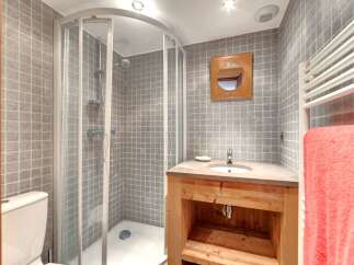 This charming bathroom features a modern shower, a stylish wooden vanity, and a sleek sink.