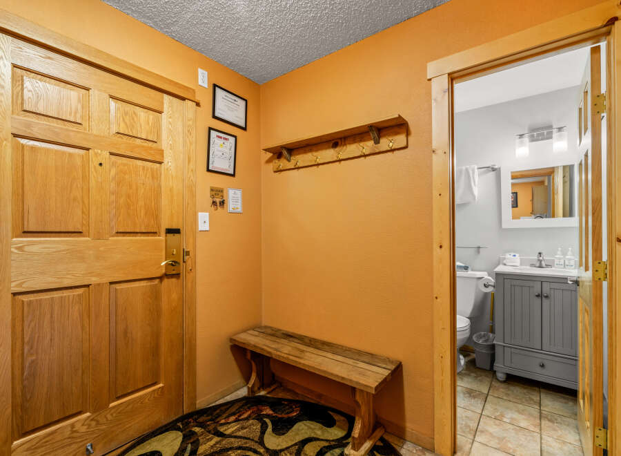 Step into this inviting entryway, featuring a warm wooden door and a charming bench.