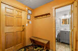 Step into this inviting entryway, featuring a warm wooden door and a charming bench.