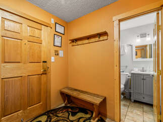 Step into this inviting entryway, featuring a warm wooden door and a charming bench.
