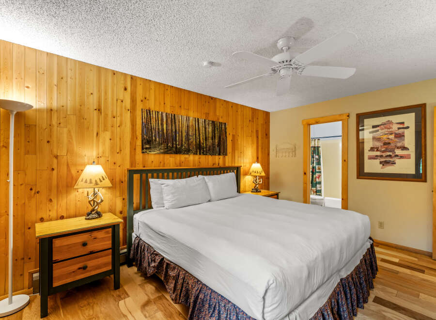 This cozy bedroom features a rustic wooden wall and a comfortable bed, perfect for a relaxing getaway.