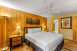 This cozy bedroom features a rustic wooden wall and a comfortable bed, perfect for a relaxing getaway.