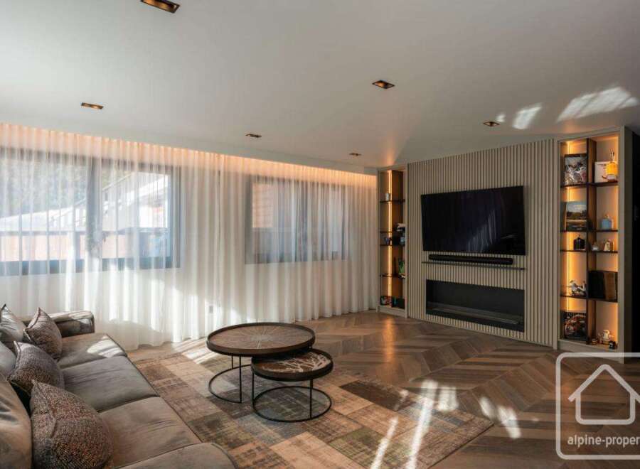 Experience luxury living in this stunning property, featuring a modern living room with a sleek fireplace and a large flat-screen TV.