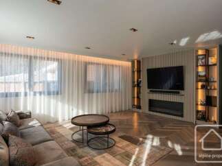 Experience luxury living in this stunning property, featuring a modern living room with a sleek fireplace and a large flat-screen TV.
