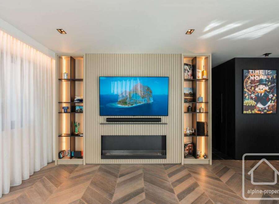 Experience luxury living in this stunning property featuring a modern entertainment center with a sleek fireplace and built-in shelving.