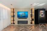 Experience luxury living in this stunning property featuring a modern entertainment center with a sleek fireplace and built-in shelving.