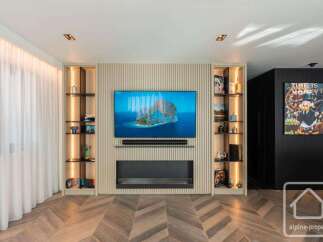 Experience luxury living in this stunning property featuring a modern entertainment center with a sleek fireplace and built-in shelving.