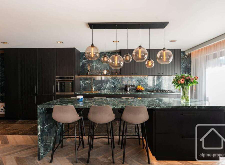 Experience luxury in this stunning kitchen featuring a striking marble countertop and sleek black cabinetry.