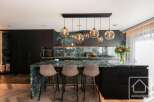 Experience luxury in this stunning kitchen featuring a striking marble countertop and sleek black cabinetry.