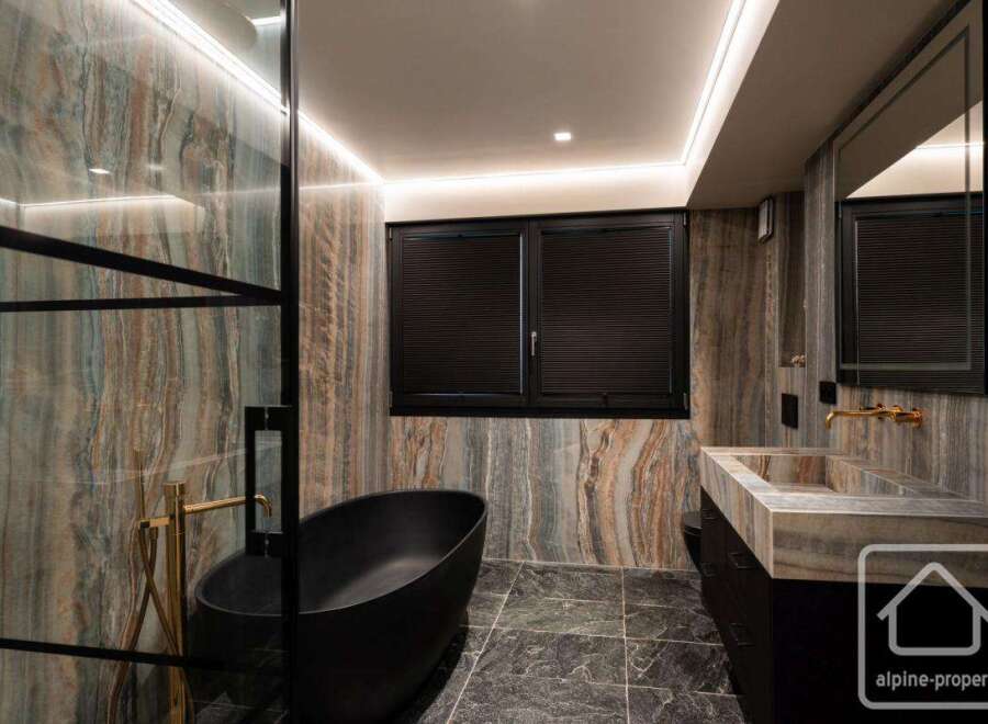 Experience luxury in this stunning bathroom featuring a sleek black bathtub and elegant gold fixtures.