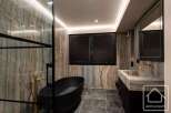 Experience luxury in this stunning bathroom featuring a sleek black bathtub and elegant gold fixtures.