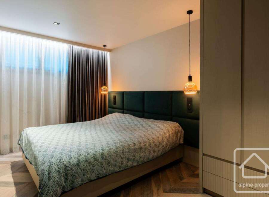Experience luxury in this stunning bedroom featuring a plush, upholstered headboard and stylish pendant lighting.