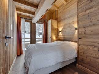 Experience the warmth of this cozy bedroom, featuring stunning wooden walls and ceilings that create a rustic ambiance.