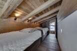 This cozy bedroom features a rustic wooden ceiling and walls, creating a warm and inviting atmosphere.