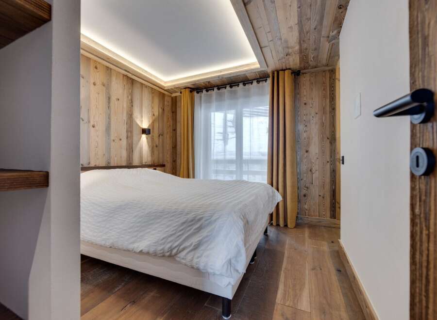 This cozy bedroom features a stunning wooden ceiling and walls, creating a warm and inviting atmosphere.