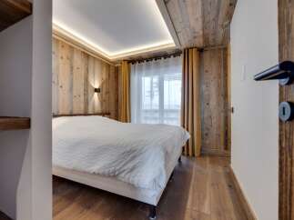 This cozy bedroom features a stunning wooden ceiling and walls, creating a warm and inviting atmosphere.