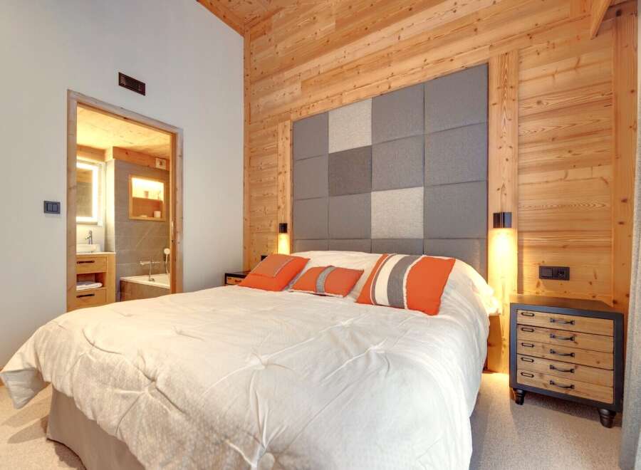 This cozy bedroom features a stunning wooden accent wall and ceiling, creating a warm and inviting atmosphere.