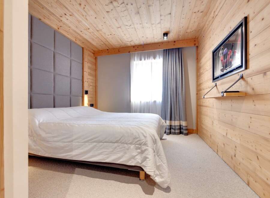 This cozy bedroom features a stunning wooden ceiling and walls, creating a warm and inviting atmosphere.