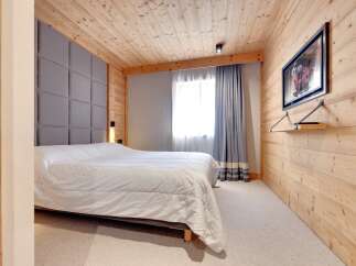 This cozy bedroom features a stunning wooden ceiling and walls, creating a warm and inviting atmosphere.
