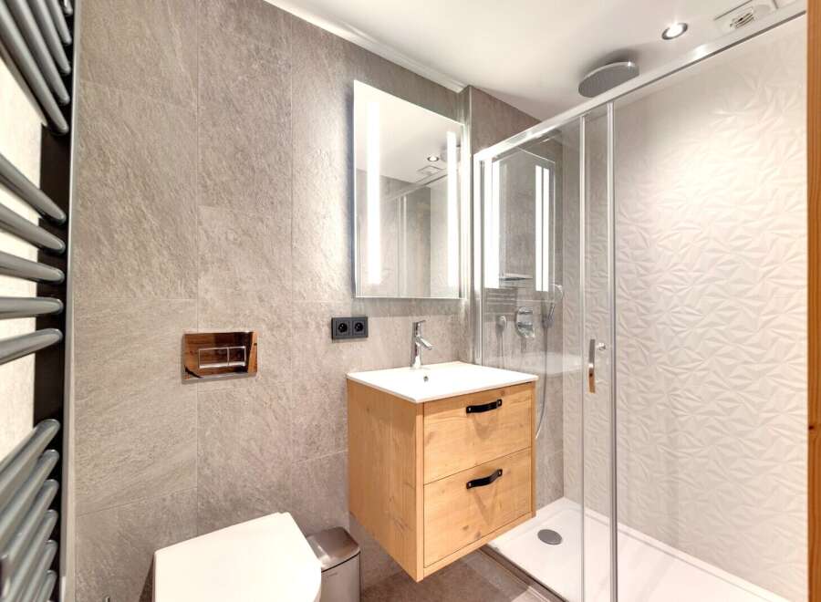 Step into a modern bathroom oasis! This stunning space features a sleek, floating wooden vanity with ample storage.